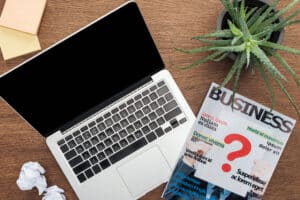 vue de dessus d'un ordinateur portable, d'un magazine professionnel et d'une plante en pot sur une table en bois