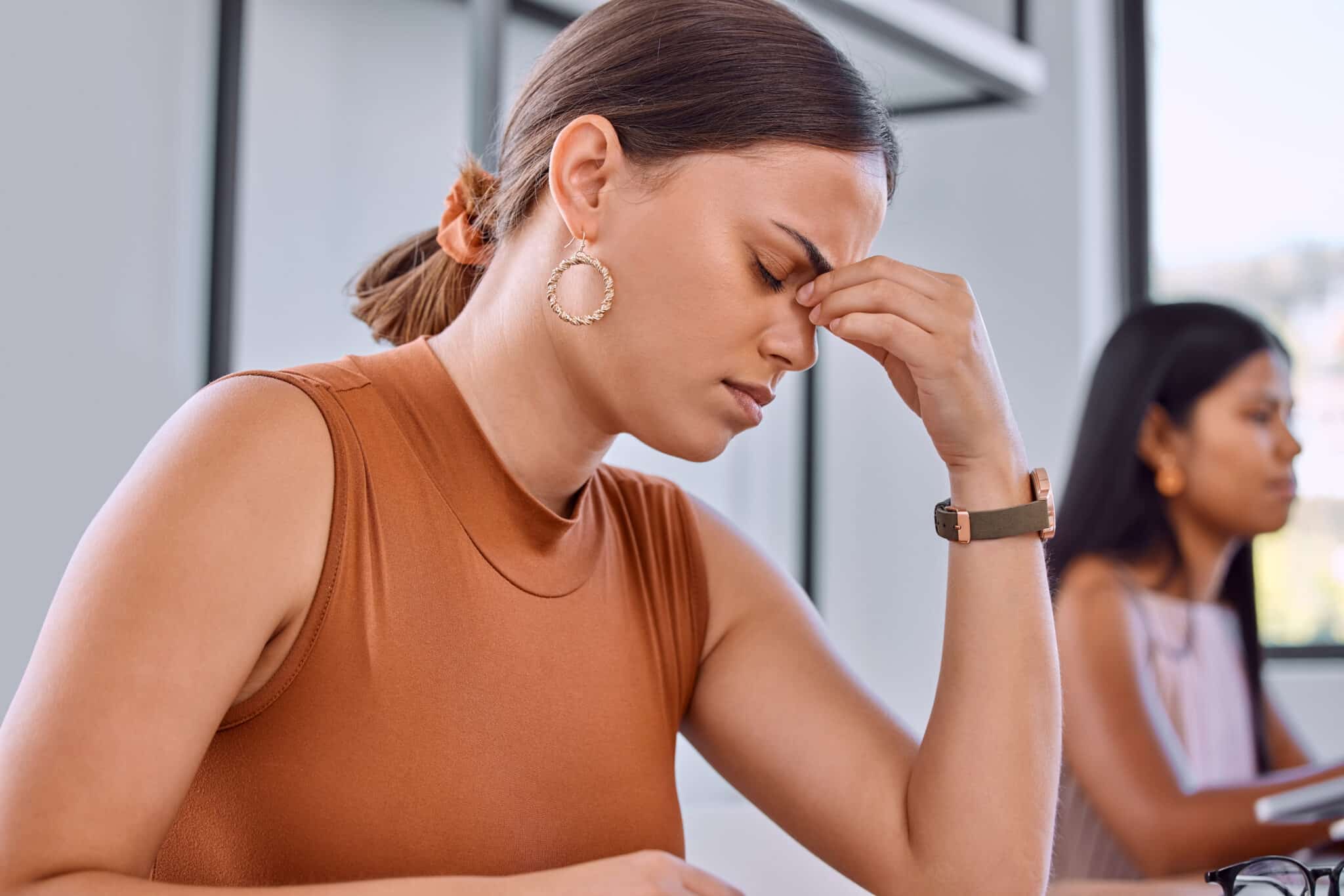 Femme métisse se tenant la tête, stressée lors d'un examen du code de la route