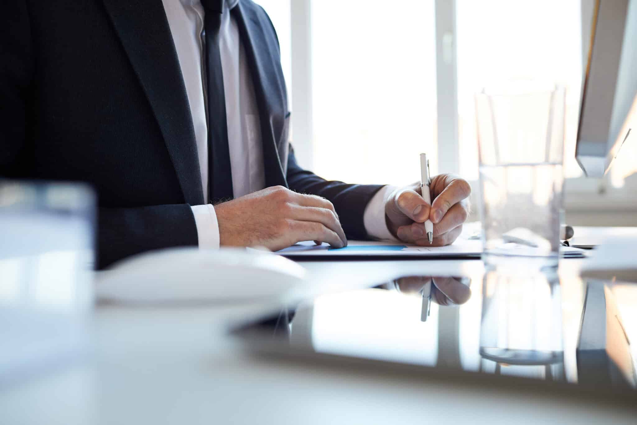 homme avec un costume tenant un stylo et qui écrit sur du papier comment avoir la qualification RGE