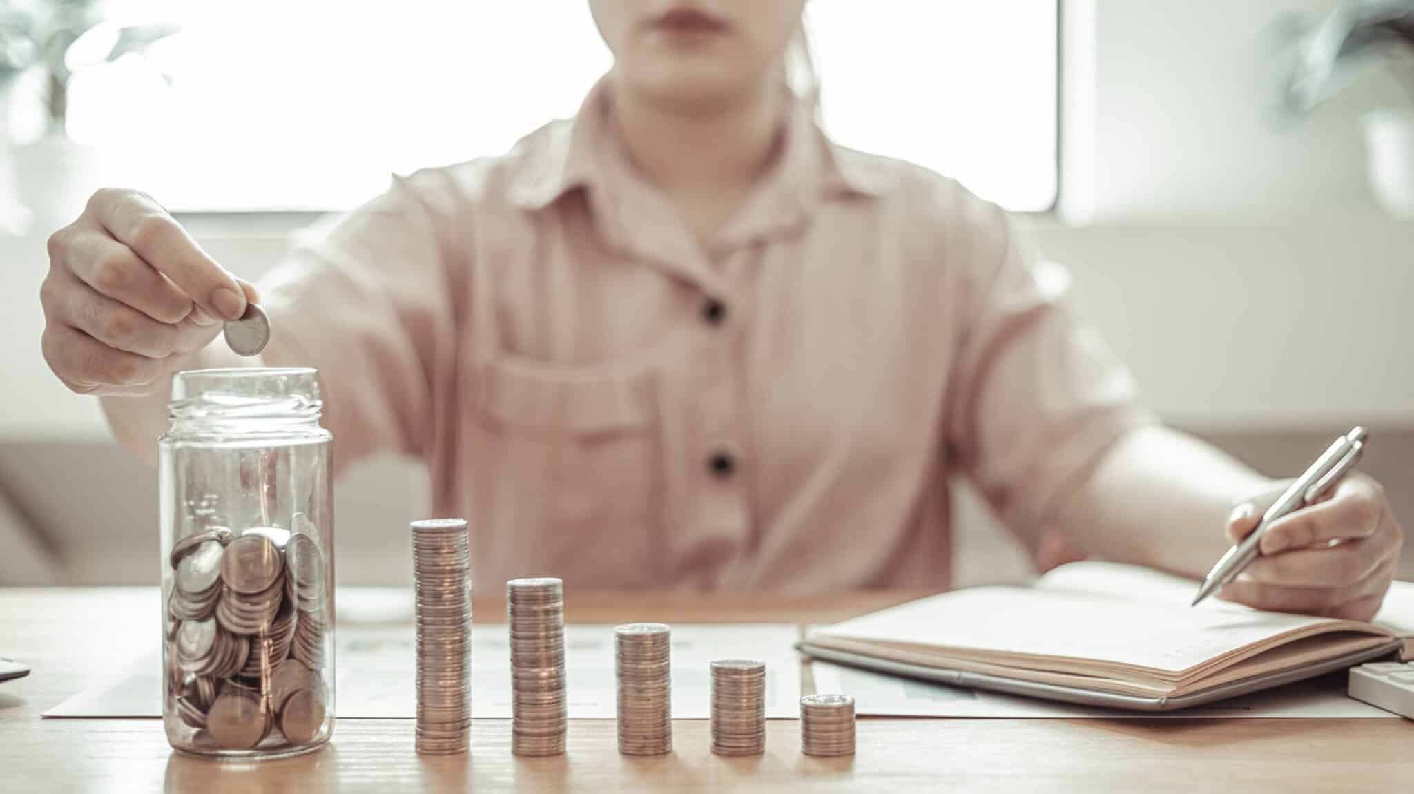 Femme qui porte une chemise rose et qui met son argent de coté pour réduire sa consommation d'énergie