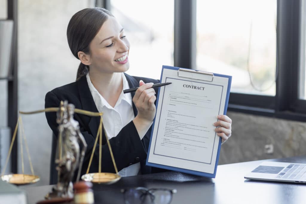 Statue de la justice et avocate en costume sur le lieu de travail avec ordinateur portable, marteau et femida au bureau.