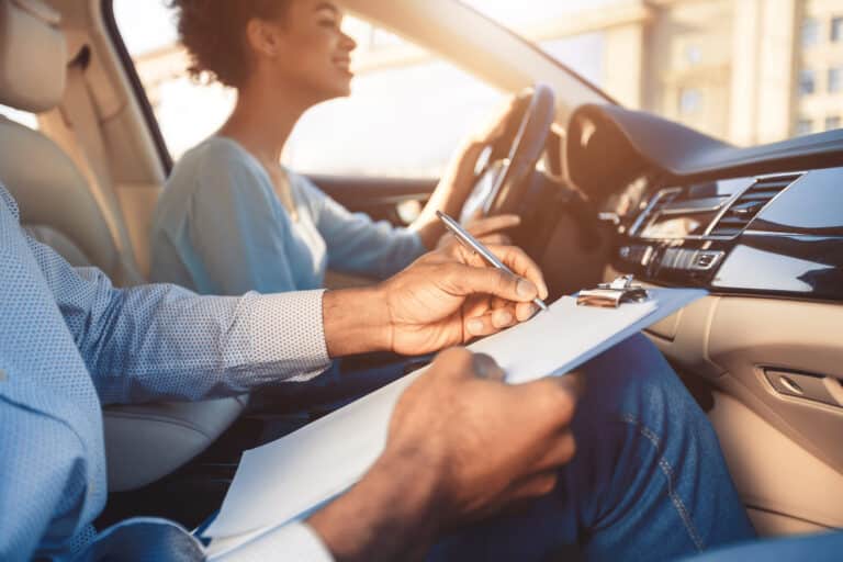 Fille afro-américaine conduisant assise avec un instructeur dans la voiture, recadrée