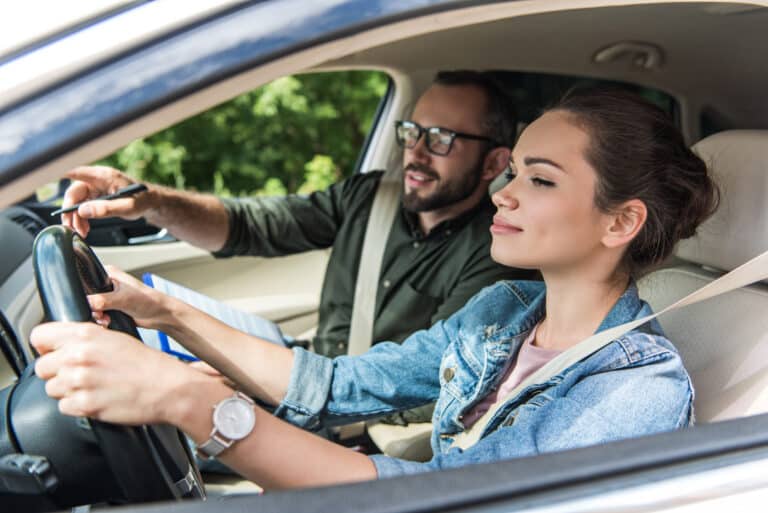 étudiant et professeur joyeux en voiture au test de conduite