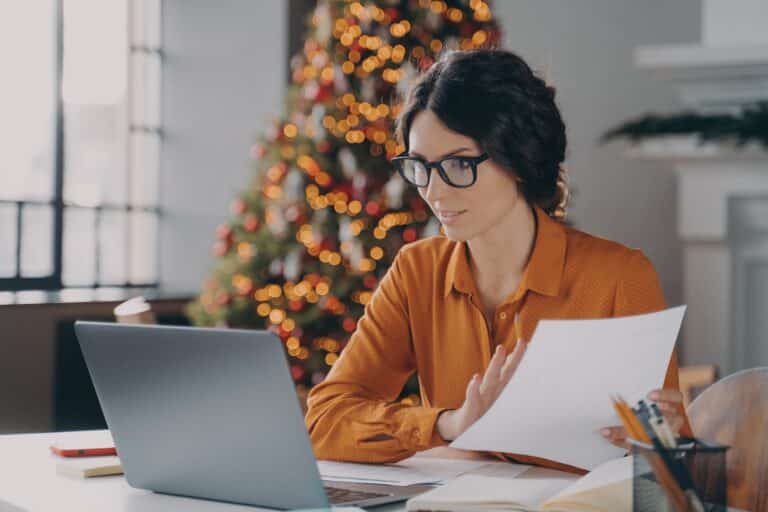 Femme d'affaires hispanique à lunettes travaillant en ligne au bureau à Noël